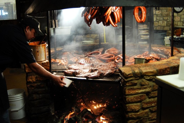 a person cooking hot dogs on a grill